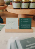 JaxKelly’s Shower Affirmation™ Cards - Abundance features two waterproof cards on a wooden holder: one card inspires with “I am courageous and confident. I invest in myself,” and the other provides usage instructions.