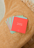 A stack of JaxKelly Shower Affirmation™ Cards - Teens rests on a textured orange blanket. The top red card says, I can always ask for help—perfect waterproof affirmation cards or Shower Affirmations for teens.