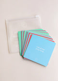 The Shower Affirmation™ Cards - Teens by JaxKelly are colorful, waterproof affirmation cards for teens. The top blue card states I am proud of my body, and the set comes with a translucent zippered pouch on a light surface.