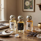 Three perfume bottles on a wooden table with decorative elements and a framed botanical print in the background.