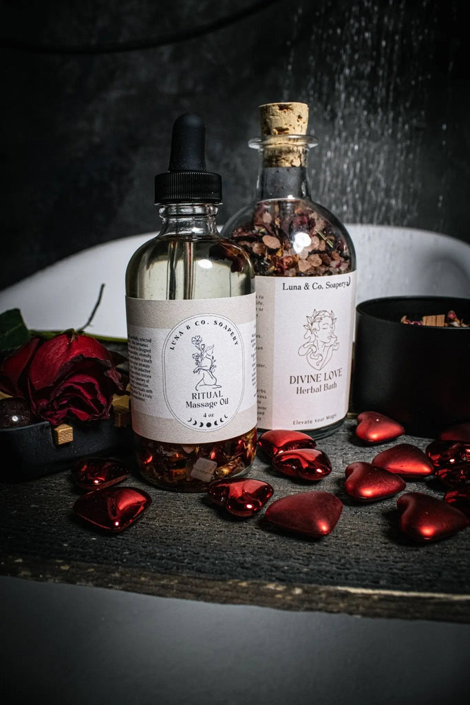 The Divine Love Ritual Kit by Luna & Co. Soapery rests on a dark tray with red rose petals and heart-shaped stones, creating a romantic self-love spa ambiance.