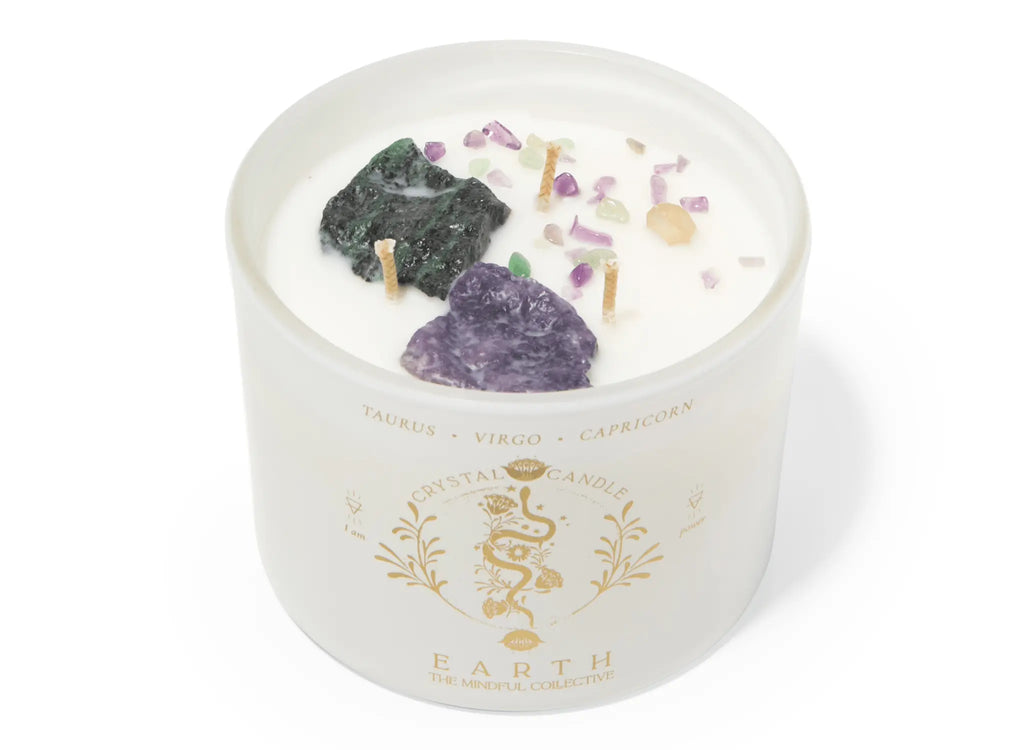 The Earth Elements Candle 12oz by THE MINDFUL COLLECTIVE is a white crystal candle in a frosted glass jar with zodiac and snake designs, topped with crystals—ideal as an Earth Signs Candle for Taurus, Virgo, or Capricorn.